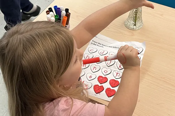 Image of girl at her desk raising her hand.